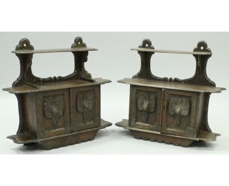 A pair of Victorian carved oak wall cabinets in the Black Forest taste, the twin cupboard doors decorated with hanging dead g