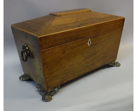 An early 19th Century rosewood tea caddy of sarcophagus form with boxwood inlaid decoration, opening to reveal a faux rosewoo