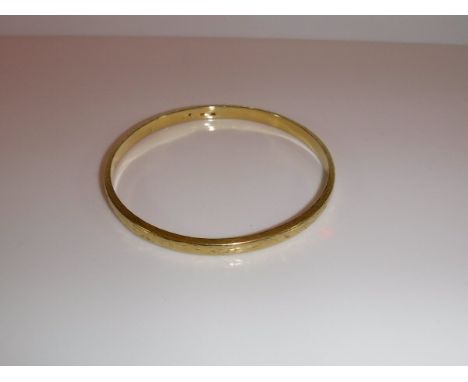 A 585 yellow metal "Slave Bangle" of hollow box form with engraved scrolling floral decoration stamoped "585" to interior, ap