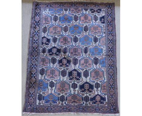 A Persian rug, the central panel set with repeating hook motifs on a cream ground with stylised flower heads on a pink, light