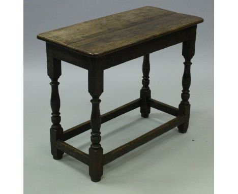 An 18th Century oak side table, the two plank top above a plain frieze, raised on turned and ringed supports to block feet un