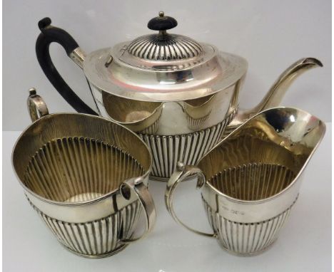 A late Victorian silver three piece tea set comprising teapot, twin-handled sucrier and milk jug, all of tapered oval form wi