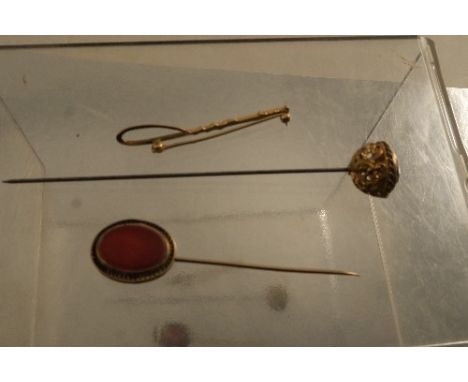 A 19th century yellow metal hat pin, set with an amethyst with pierced scroll frame,&nbsp; together with an onyx stick pin an