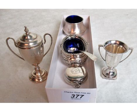 Two small silver trophy cups, one with cover, a bun form silver patch box, two open salts, one with ribbon tied floral swag d