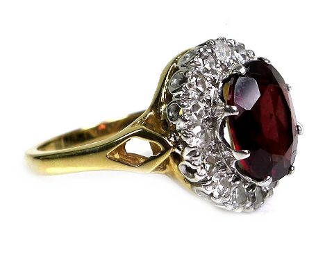 An 18ct yellow gold dress ring, set with an oval cut red coloured stone, possibly garnet, approximately 10 by 8 by 6.5mm, sur