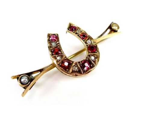A Victorian rose gold, ruby diamond and pearl horseshoe brooch, set with seven rubies of graduated size and six old cut diamo