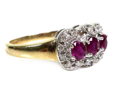 An 18ct gold and ruby three stone ring, each stone of approximately 4 by 3.5mm, with diamond chips to the surround, size T, 3