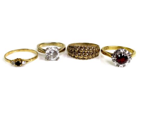 A group four rings, comprising an 18ct gold flowerhead ring, set centrally with a round cut red stone, 6 by 4mm, surrounded b