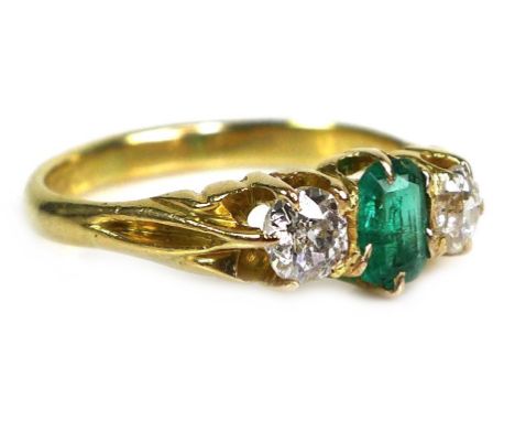 An unmarked gold, diamond and emerald three stone ring, with a central emerald cut Colombian emerald of approximately 5.0 by 