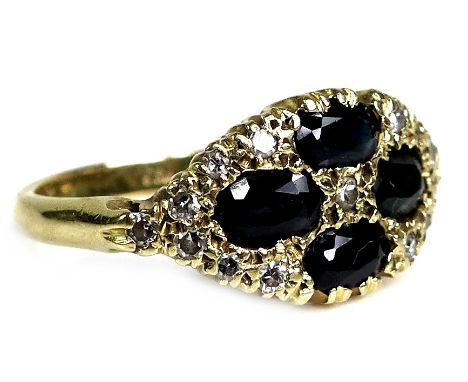 An 18ct yellow gold ring, set with four oval cut dark blue sapphires, 6 by 3 by 3mm, amongst fifteen circular cut diamonds, e