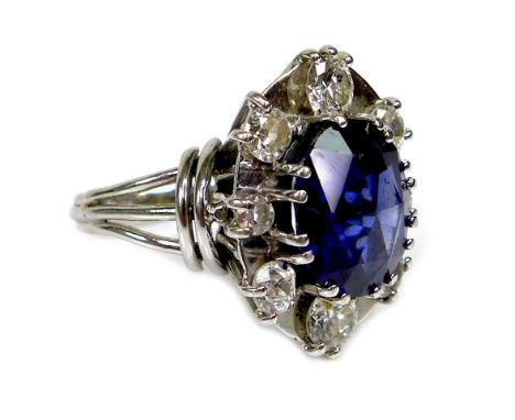 A sapphire and diamond dress ring, the oval geometric cut royal blue sapphire of approximately 12 by 10mm and surrounded by e