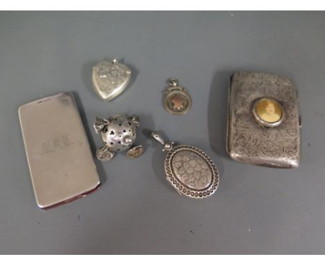 A silver cigarette case with portrait insert a silver 'magic' wallet, a silver rattle, a silver heart shaped vesta, a locket 