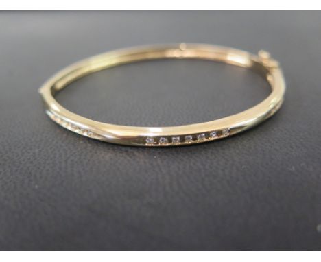 A 9ct gold diamond bangle - The three brilliant-cut diamond lines to the plain bangle - Hallmarked Birmingham - Inner diamete