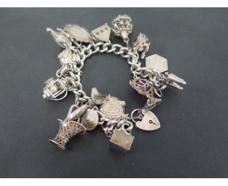A silver curb-link bracelet - Suspending assorted charms - Hallmarked London - Length 19cms - Weight approx 28.0gms
Condition