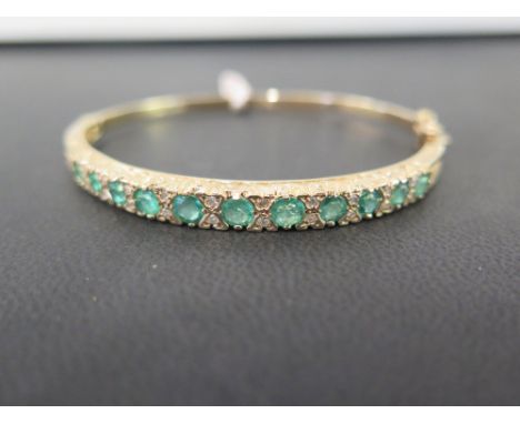 A 9ct gold emerald and diamond hinged bangle - To the scrolled gallery and plain half bangle - Hallmarked London - Inner diam