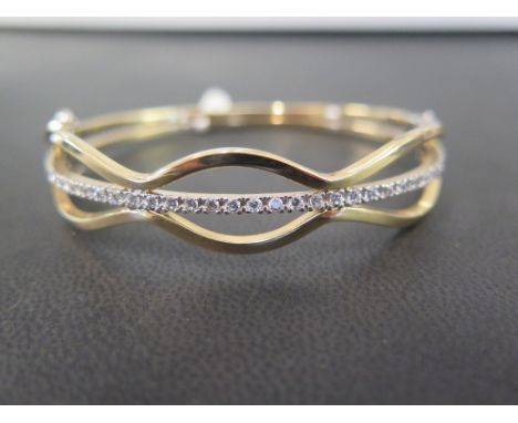 A 9ct gold diamond diamond bangle - Of openwork design the brilliant-cut diamond line to the scalloped sides - Hallmarked Lon