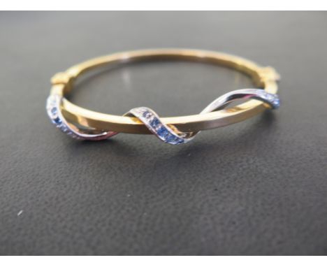 A bi-colour hinged bangle - With sapphire set twist detail - Stamped 750 (18ct) - Inner diameter 6cms - Weight approx 15.0gms