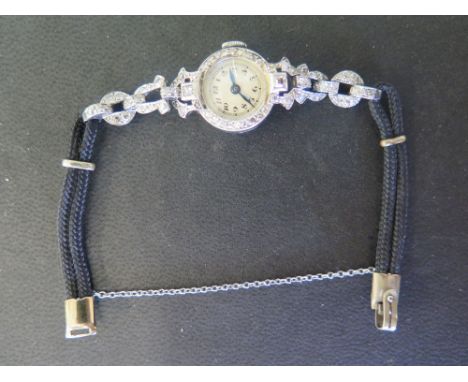 A Ladies diamond and cocktail watch with diamond and half strap with cord strap below - the watch has a white enamel face wit