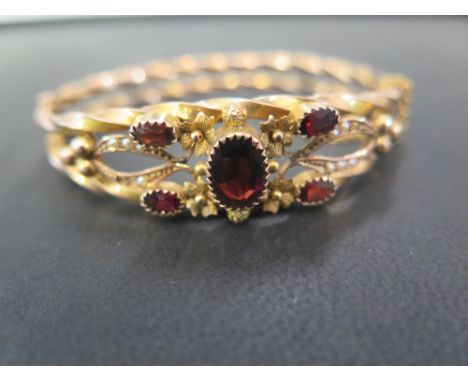 An early 20th century 9ct gold garnet and seed pearl hinged bangle - Hallmarked Chester, 1907 - Inner diameter 6cms - Weight 