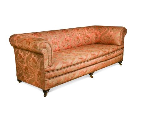 A Victorian scroll-arm three-seat Chesterfield sofa,  on turned oak legs with castors, upholstered in pink and gold floral si