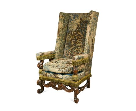 A Carolean carved walnut  and oak needlework upholstered wingback armchair, 17th century, raised on scrolled front feet unite