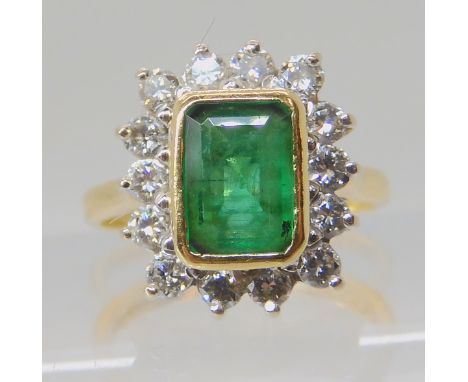 AN 18CT GOLD EMERALD AND DIAMOND RING set with a step cut emerald of approximate dimensions 7.5mm x 5.5mm x 2.8mm, surrounded