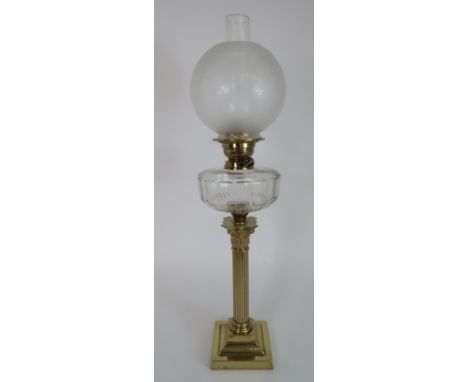 A BRASS COLUMN OIL LAMP with clear glass font and Duplex marked wheels, the shade with etched decoration, 75cm to top of funn