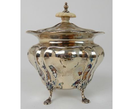 A SILVER TEA CADDY by Walker &amp; Hall, Sheffield 1903, of bombe shape, the removable cover with ivory finial on four shell 