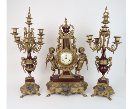 AN ITALIAN IMPERIAL CLOCK GARNITURE the dial with Roman numerals, standing on gilt metal and burgundy enamel base, with fauns