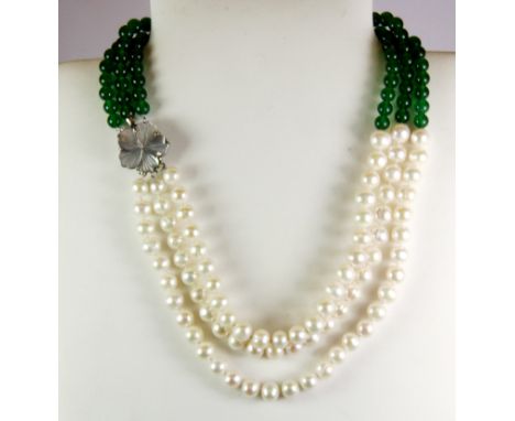 A three row pearl and jade bead necklace on a carved mother of pearl clasp.