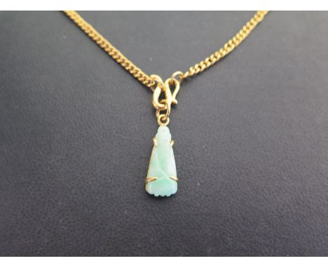 A carved jade pendant suspended from a curb-link chain - With foreign marks indicating high carat gold - Length of pendant 3c
