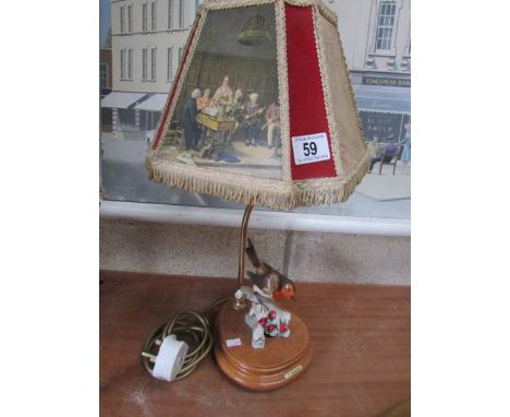 A vintage table lamp with shade surmounted robin.