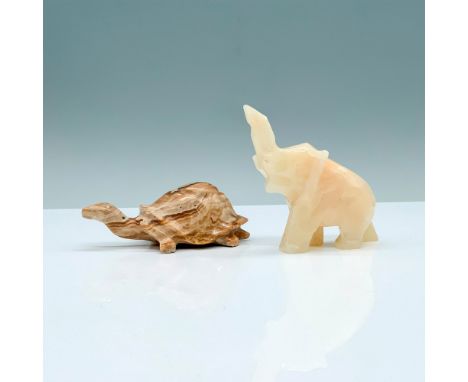 A pair of 2 stone animal figurines, an elephant with a raised trunk carved out of white stone, and a tortoise in motion carve