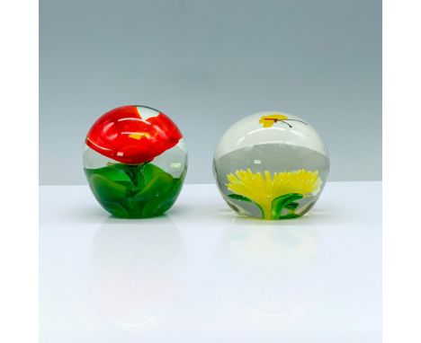 A set of two paperweights, one with a yellow flower with a butterfly flying overhead, the other a red flower with a yellow ce