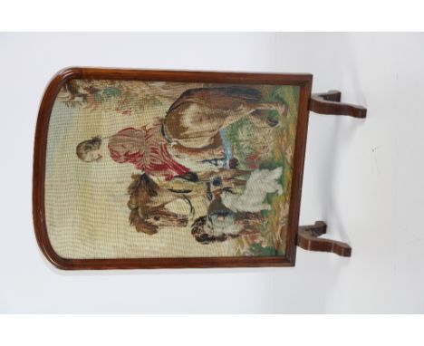 A Victorian walnut framed Firescreen, with central needlework tapestry depicting a young lady on horseback, with dogs in a la