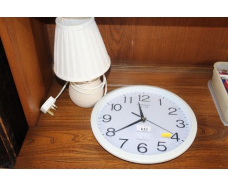 A modern wall clock and a table lamp and shade