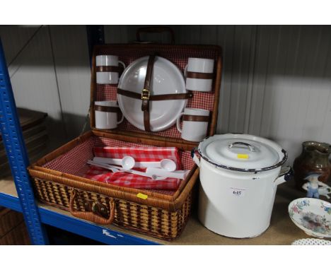 An enamel twin handled container with lid and a wicker picnic basket and contents