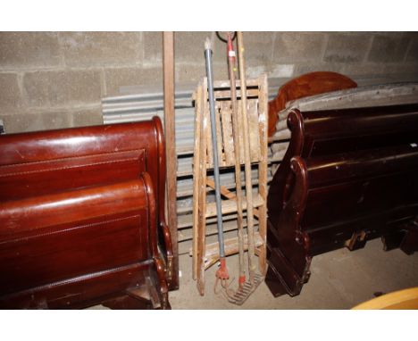 A wooden step ladder and three long handled gardening tools 