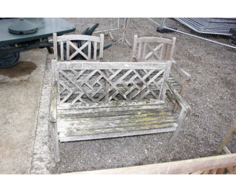 A teak garden bench with matching teak armchairs with integral table