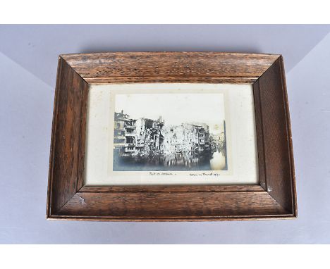 A gelatin silver print of war damage in the city of Verdun, damaged buildings on the banks of the Meuse, titled in ink 'Part 