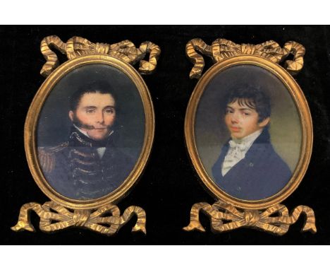 A pair of giltwood oval portrait miniature frames, moulded and carved, each with ribbon tied crests, containing printed portr