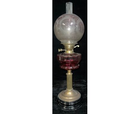 A 19th century oil lamp, frosted globular shade, ruby glass font, brass columnar support, spreading circular base, mounted on