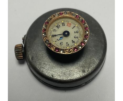 An early 20th century gun metal buttonhole watch, white enamel dial, Arabic numerals, the dial set with ruby and diamond chip