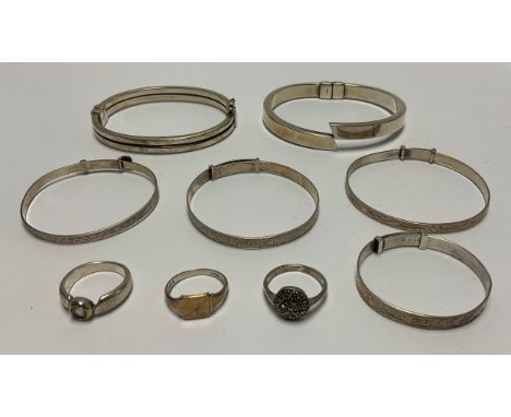 A silver hinged bangle, marked 925; other sterling silver bangles, three sterling silver rings, 71g 