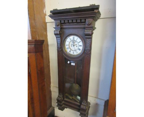 Vienna oak cased wall clock of ornate architectural form, the enamel dial with Roman numerals and visible escapement flanked 