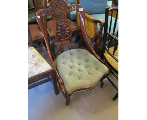 Victorian walnut low seat nursing chair with a pierced floral carved back above a button upholstered seat on cabriole support