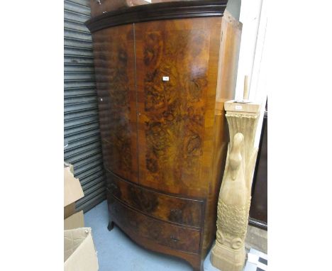 Early 20th Century figured walnut bow front wardrobe, the moulded cornice above a pair of panelled doors and two drawers with