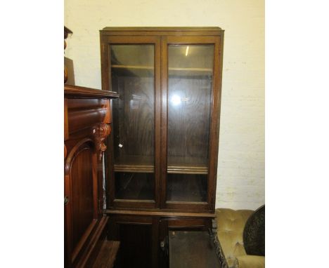 20th Century oak bookcase having two glazed doors enclosing adjustable shelves above a further two panel doors on stile end s