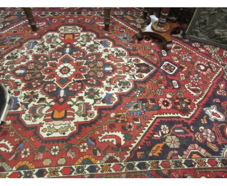 20th Century Kurdish carpet with a medallion and all-over stylised floral design on a red ground with borders, 10ft x 7ft app