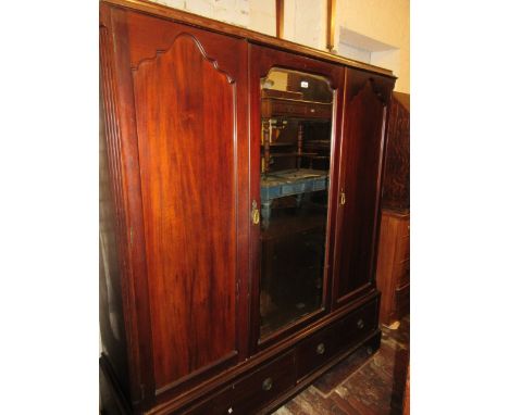 Edwardian mahogany three door wardrobe having central mirrored door over two short drawers with brass ring handles, raised on